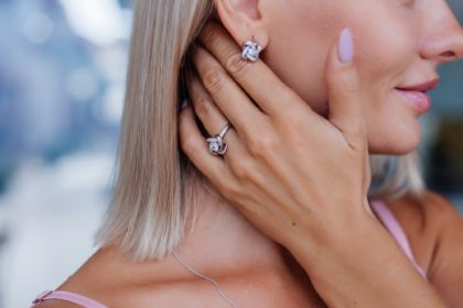 Close shot of rich luxury woman in dress hand and ear wearing earings and ring on finger.